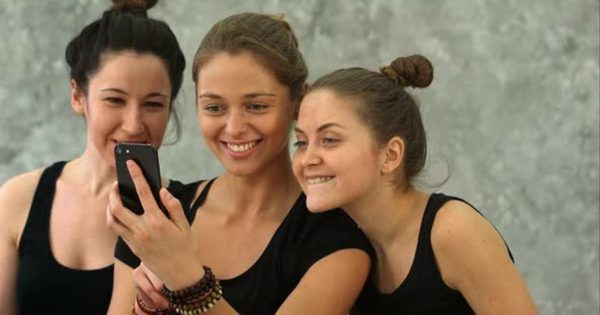 女性瑜伽训练休息时刻场景大洋岛精选视频素材 Three Young Women Browsing Internet Using Smartphone After Workout at Yoga Class