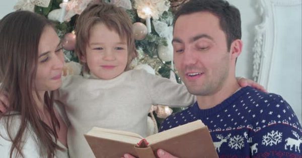 温馨家庭阅读书本场景大洋岛精选视频素材 Happy Family of Three Reading Together on Christmas Evening