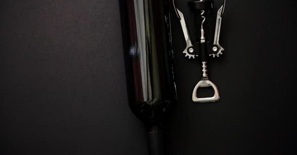红酒瓶&酒瓶器黑色哑光大洋岛精选背景视频素材 Red Wine Bottle and Corkscrew on Black Matte Background.